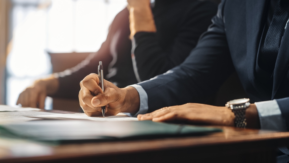 Attorney Signing Agreement Photo of a person at the table writing on the paper